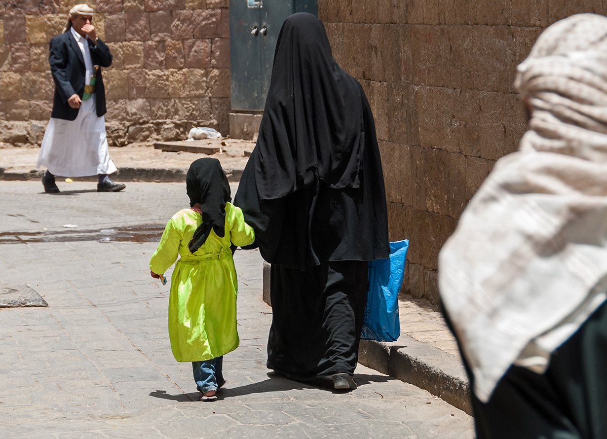 Foto de uma mulher usando uma burca preta. Ela está ao lado de uma menina usando um lenço preto. (crédito: dinosmichail – iStock)