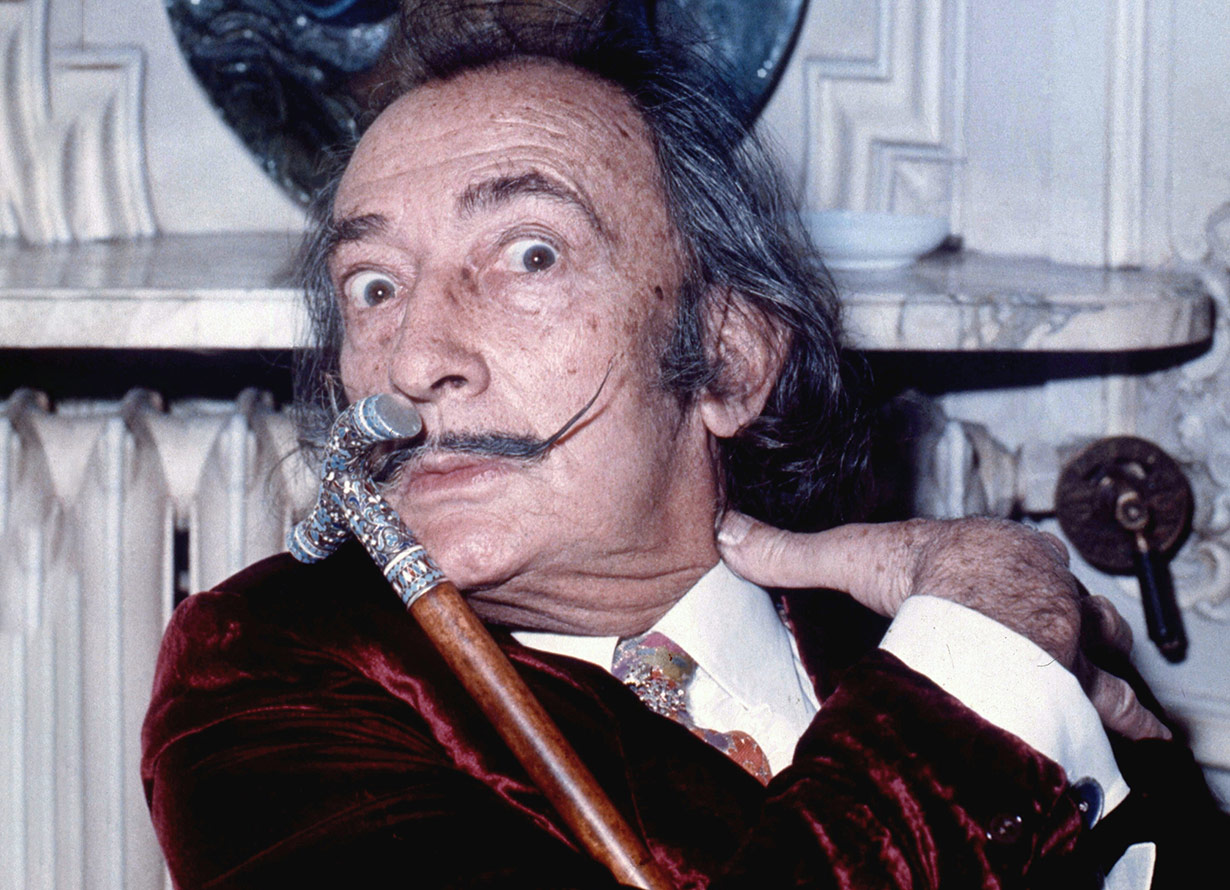 Foto do pintor surrealista Salvador Dalí. Ele está com os olhos arregalados e tem cabelos grisalhos, uma sobrancelha grossa e um bigode longo com as pontas finas para cima (crédito: Allan Warren/Wikimedia Commons)