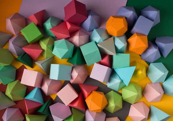 Foto vista de cima de sólidos platônicos de origami modular em cima de uma superfície colorida.