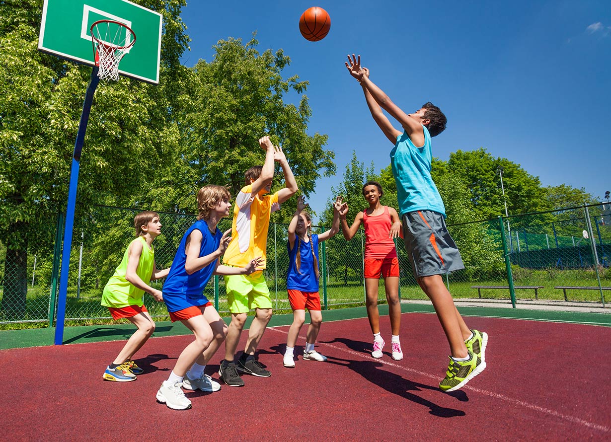 Foto de 6 crianças jogando basquete ao ar livre (crédito: SerrNovik – iStock)