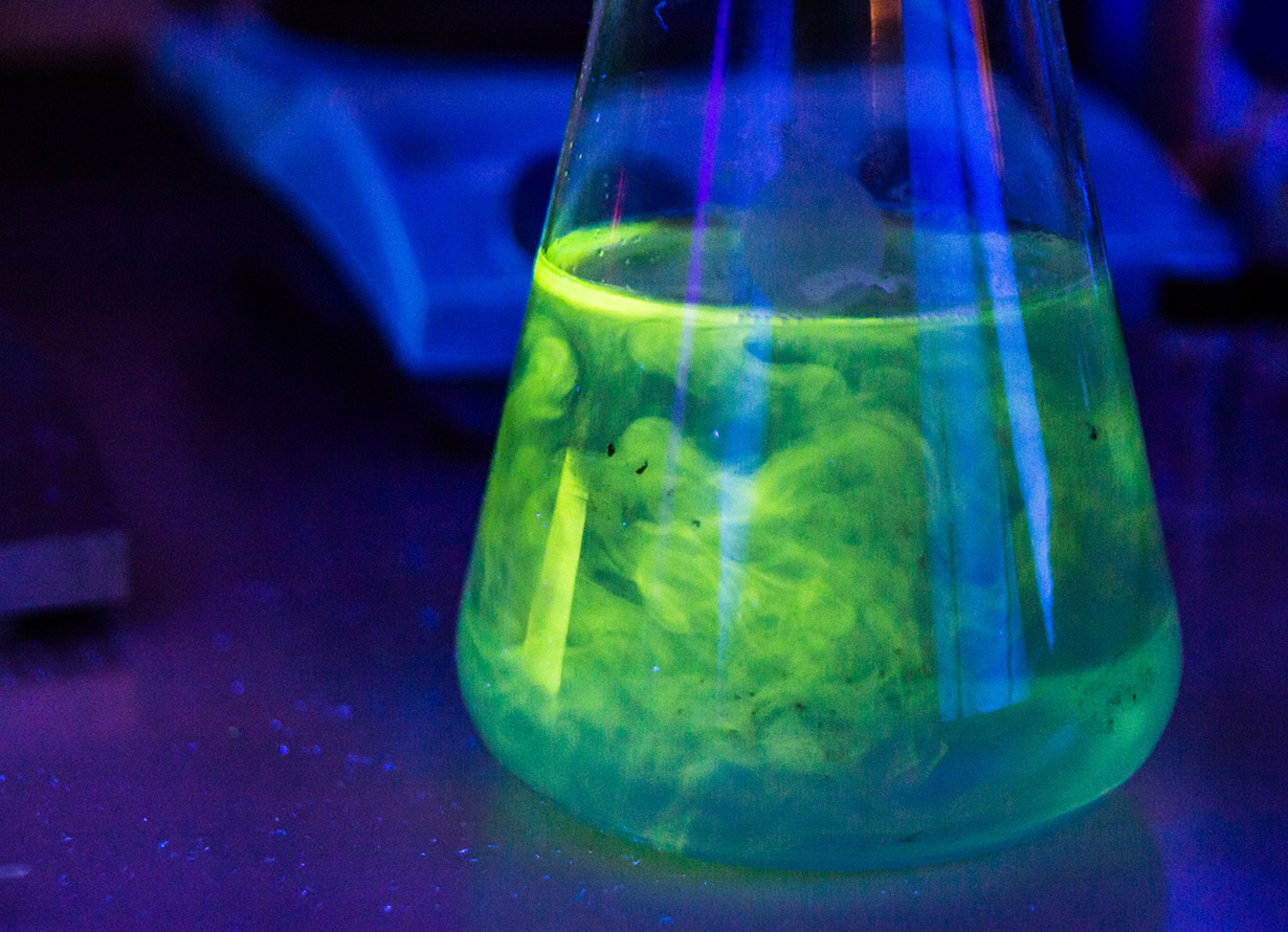 Foto em detalhe de um líquido verde dentro de um erlenmeyer (crédito: MichalLudwiczak - iStock)