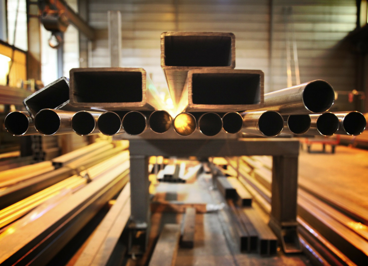 Foto de diversas barras de ferro e canos de matal dentro de uma siderúrgica