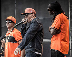 Foto dos integrantes da banda Racionais MC's durante apresentação em um palco.