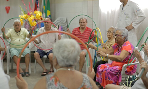 Foto de um grupo de idosos durante uma atividade física com bambolês